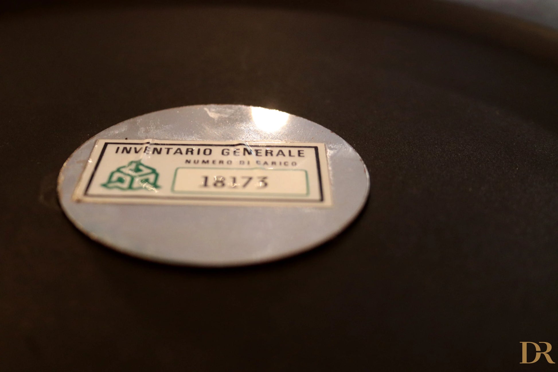 Etichetta di inventario ovale argento con testo verde e nero su appendiabiti velca paolo orlandini e velca milano