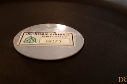 Etichetta di inventario ovale argento con testo verde e nero su appendiabiti velca paolo orlandini e velca milano